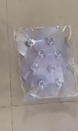 Clear plastic packaging with clear crystal-like objects on a beige surface