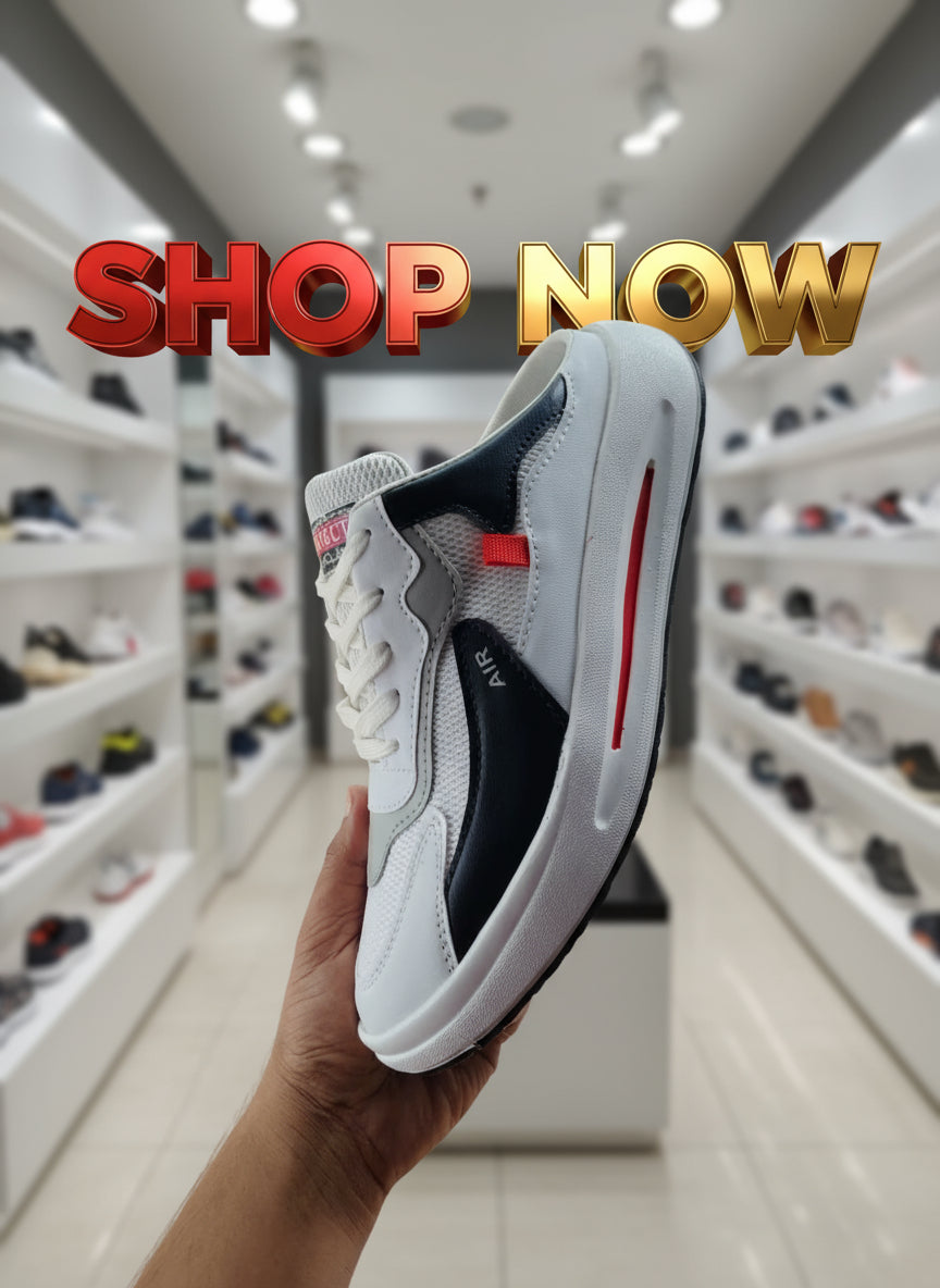 Gray and black sneaker with red accents held by a hand against a cluttered background