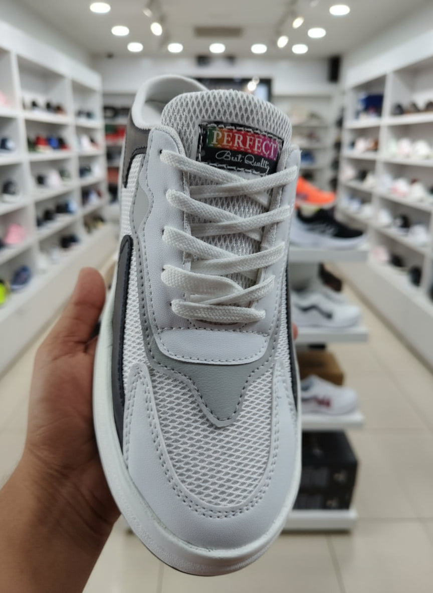 Gray sneaker held in a hand with a cluttered background