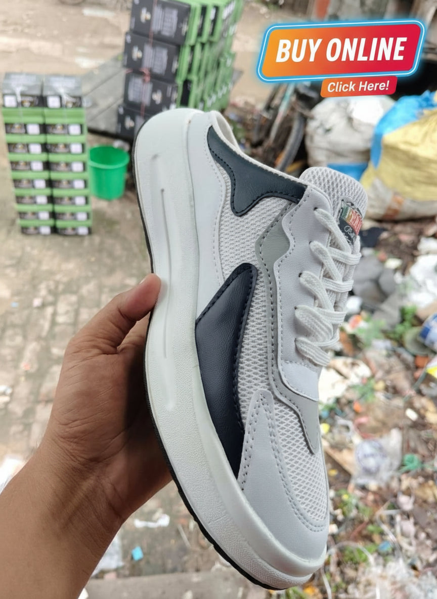 Gray and black sneaker held by a hand with a cluttered background